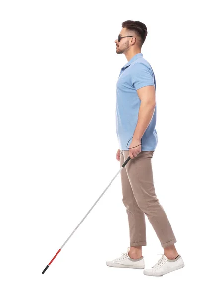 Young blind person with long cane walking on white background — Stok fotoğraf