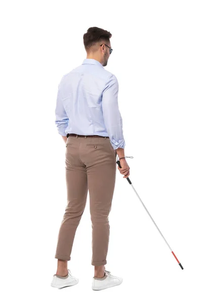 Young blind person with long cane walking on white background