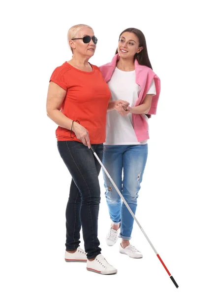 Mujer joven ayudando a una persona ciega con bastón largo sobre fondo blanco — Foto de Stock