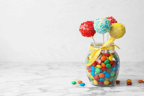 Yummy bright cake pops in glass jar full of candies on table. Space for text — 스톡 사진