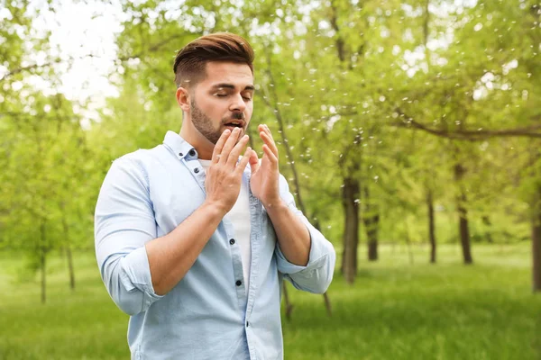 Young man suffering from seasonal allergy outdoors, space for text — Stock Photo, Image