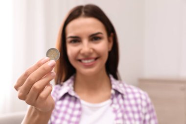 Mutlu genç kadın evde sikke tutan, el odaklanmak