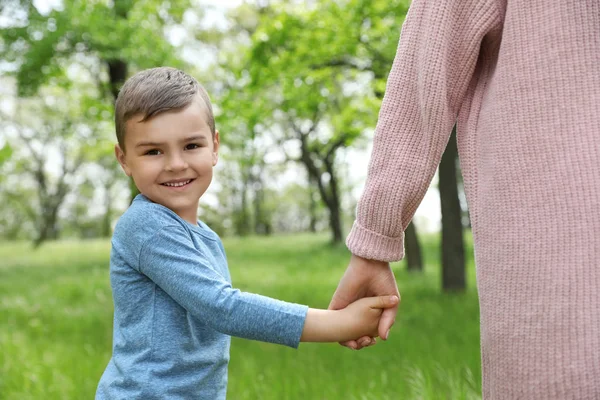 Un bambino felice che si tiene per mano con sua madre al parco. Tempo di famiglia — Foto Stock