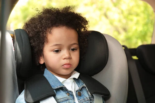 자동차 안에 혼자 안전 좌석에 앉아 귀여운 아프리카 계 미국인 소녀. 위험에 처한 어린이 — 스톡 사진