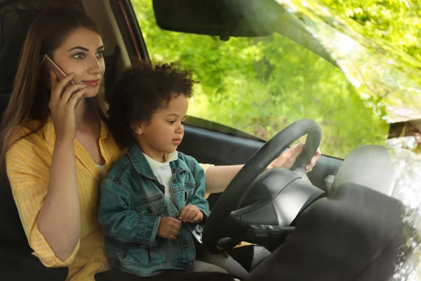 Mère avec une petite fille à genoux conduisant une voiture et parlant par téléphone. Enfant en danger — Photo