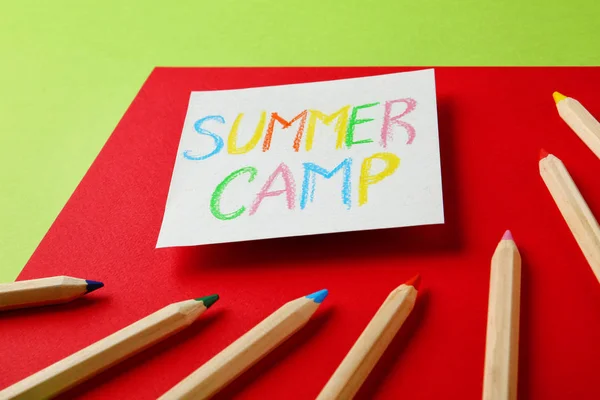 Папір з написаним текстом SUMMER CAMP та різними олівцями на кольоровому фоні — стокове фото