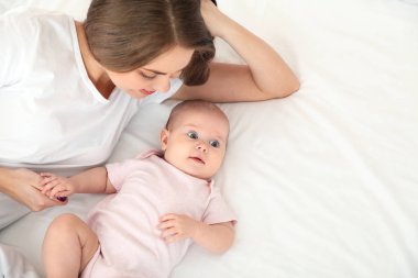 Sevimli bebek ve anne yatakta yatıyor, manzaranın üstünde. Metin için alan