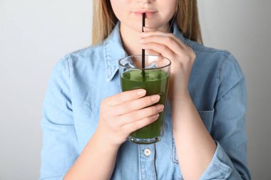 Kadın içen spirulina gri arka plan üzerinde camdan sallamak sallamak, closeup