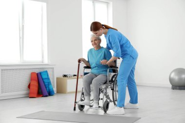 Professional physiotherapist working with elderly patient in rehabilitation center clipart
