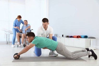 Professional physiotherapists working with patients in rehabilitation center clipart