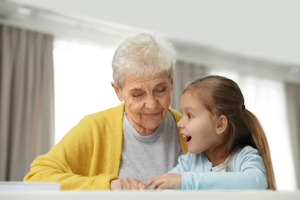 Linda chica y su abuela leyendo libro en casa — Foto de Stock