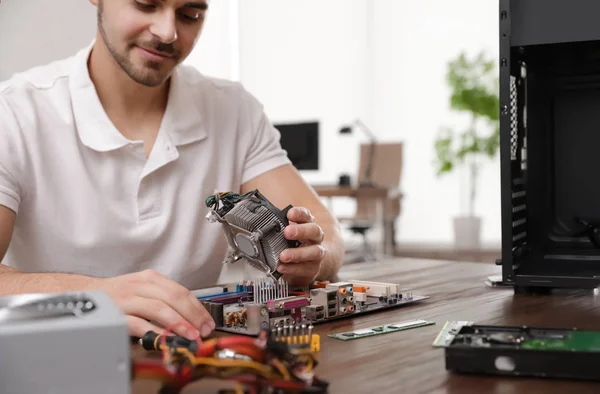 Чоловічий технік ремонтує комп'ютер за столом в приміщенні — стокове фото