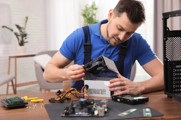 Männlicher Techniker repariert Netzteil am Tisch drinnen — Stockfoto