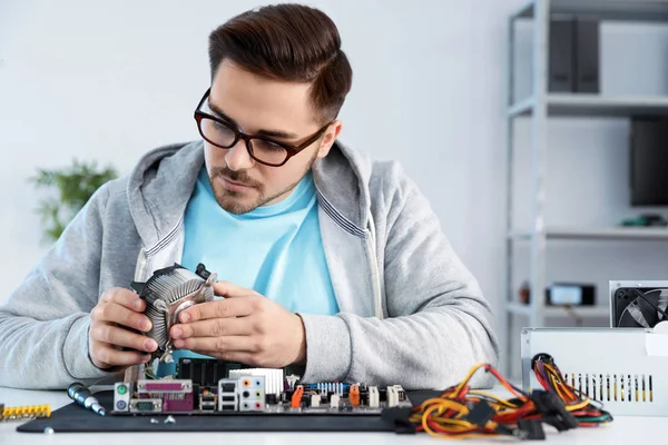 Técnico masculino reparando placa-mãe na mesa dentro de casa — Fotografia de Stock