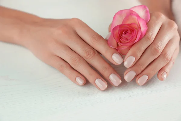 Mujer sosteniendo la flor en la mesa, de cerca. Tratamiento de spa — Foto de Stock