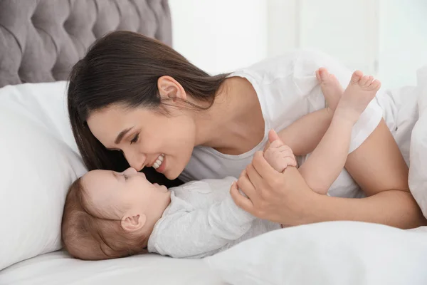 Portrait of mother with her cute baby lying on bed indoors — Stock Photo, Image