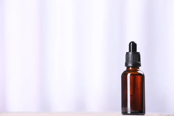 Fles etherische olie op lichte achtergrond, ruimte voor tekst. Cosmetisch product — Stockfoto