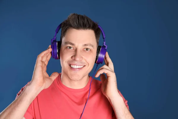 Homme appréciant la musique dans les écouteurs sur fond de couleur — Photo
