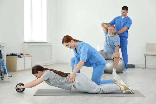 Professional physiotherapists working with patients in rehabilitation center — Stock Photo, Image