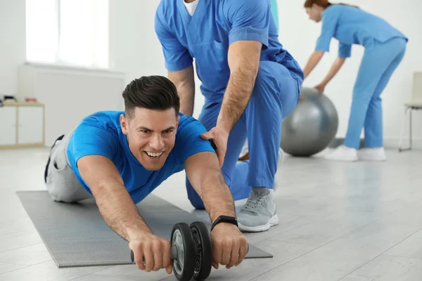 Profesionální fyzioterapeutka pracující s mužským pacientem v rehabilitačním středisku — Stock fotografie