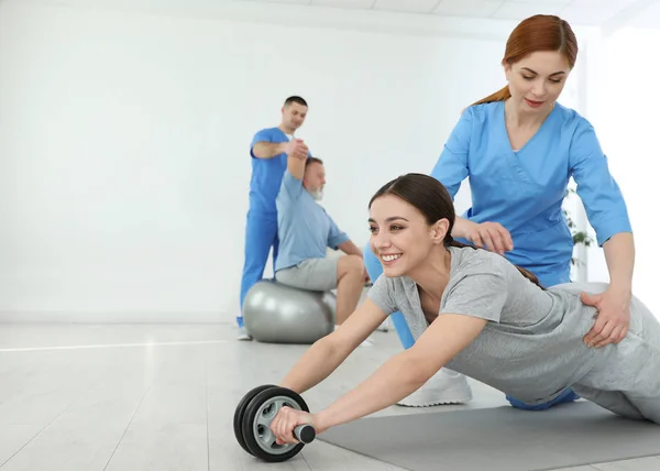 Professional physiotherapist working with female patient in rehabilitation center. Space for text — Stock Photo, Image