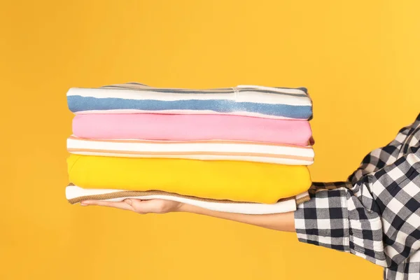 Mujer joven sosteniendo la ropa limpia en el fondo de color, primer plano — Foto de Stock