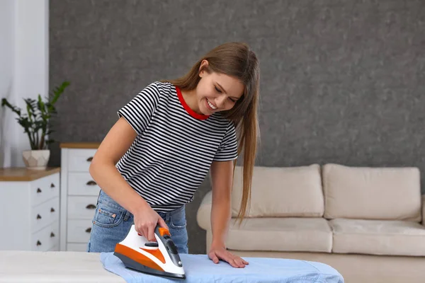 Young woman ironing clothes on board at home. Space for text — Stock Photo, Image