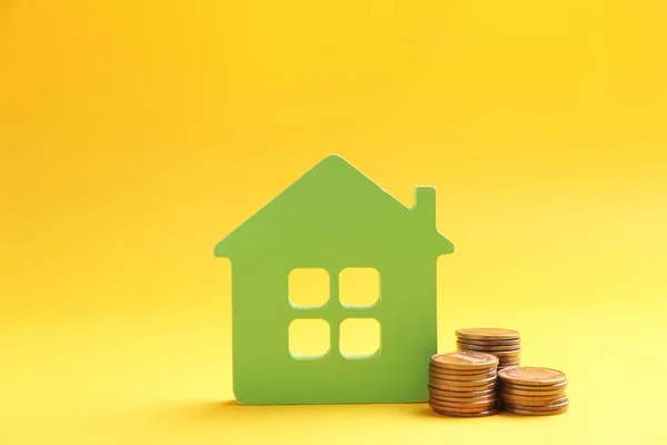 Figura da casa e moedas em fundo de cor — Fotografia de Stock