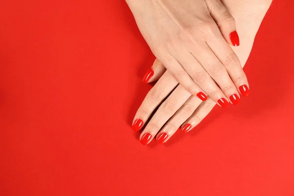 Mujer mostrando las manos cuidadas con esmalte de uñas rojo en el fondo de color, vista superior. Espacio para texto — Foto de Stock