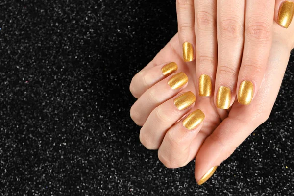 Woman showing manicured hands with golden nail polish on black background, closeup. Space for text — Stock Photo, Image