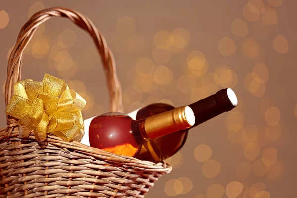 Bottles of wine in wicker basket with bow against blurred lights
