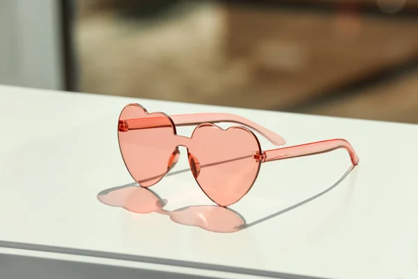 Lunettes de soleil élégantes en forme de coeur sur la table sur fond flou. Espace pour le texte — Photo