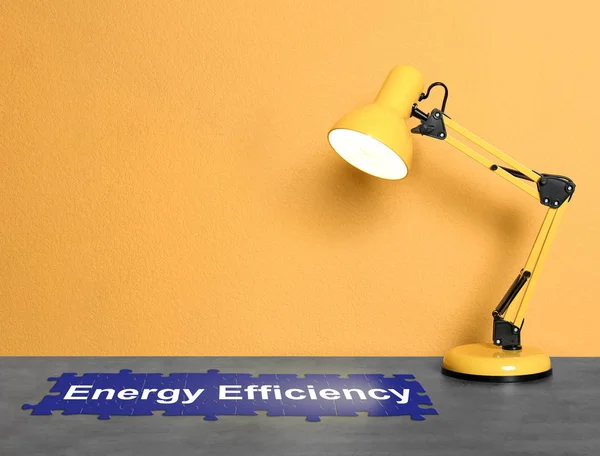 Moderní lampa na stole blízko barevné zdi, prostor pro text. Koncepce energetické účinnosti — Stock fotografie