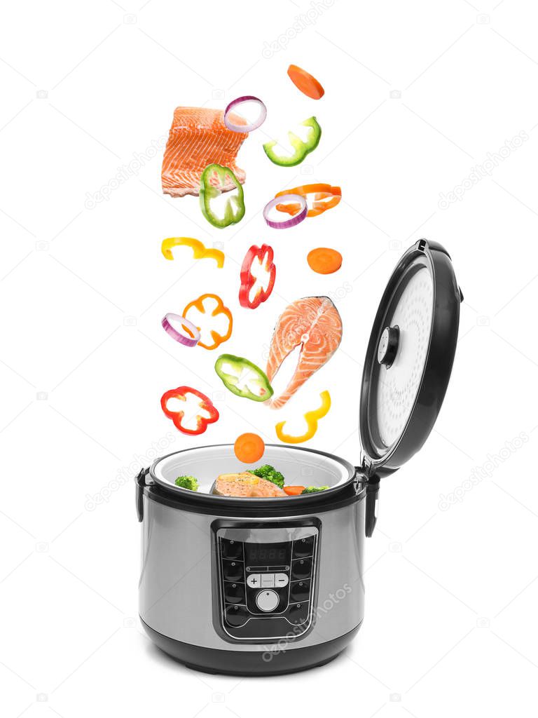 Different delicious fresh ingredients falling into modern multi cooker on white background