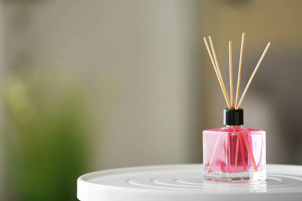 Aromatic reed air freshener on table against blurred background
