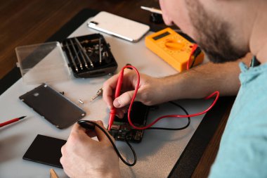 Teknisyen tamir dükkanında masada cep telefonu kontrol, closeup