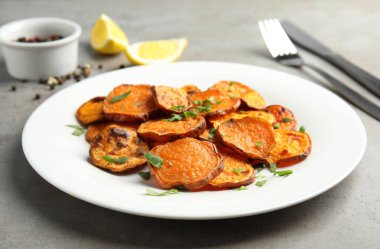 Gri masada pişmiş tatlı patates dilimleri ile Tabak, closeup