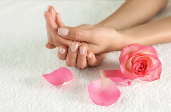 Wanita dengan tangan halus dan bunga di handuk, tutup. Perawatan spa — Stok Foto