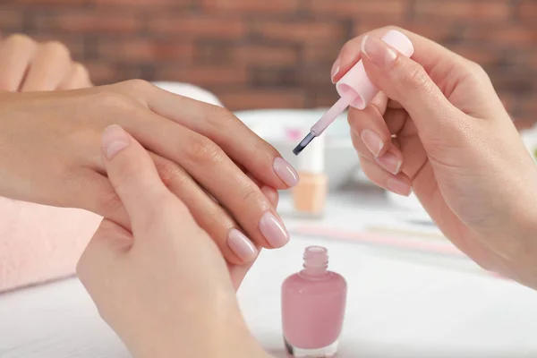 Manicura aplicando esmalte en las uñas del cliente en la mesa, primer plano. Tratamiento de spa —  Fotos de Stock