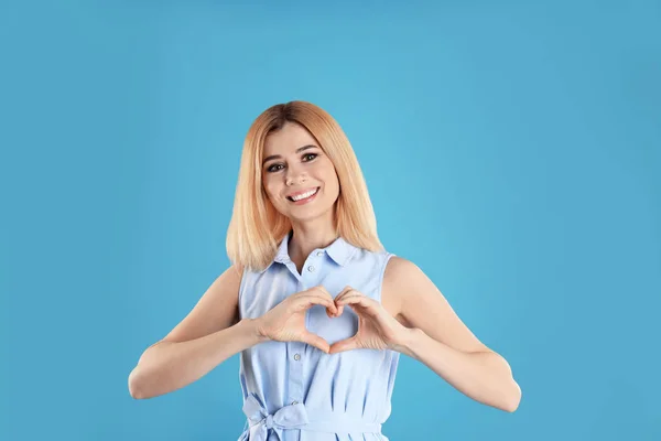 Portret van vrouw maken hart met haar handen op een achtergrond met kleur — Stockfoto