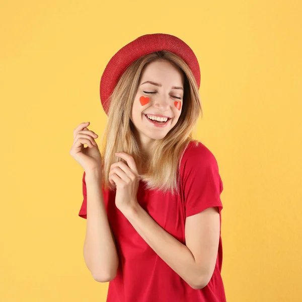 Porträtt av kvinna med hjärtformade klistermärken på ansiktet mot färg bakgrund — Stockfoto