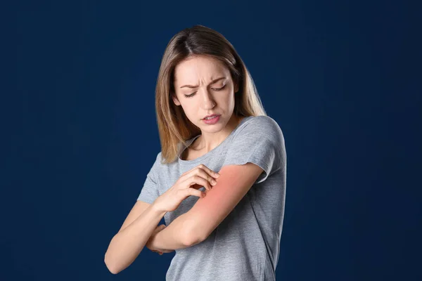 Retrato de mujer arañando brazo sobre fondo de color. Síntoma de alergia — Foto de Stock
