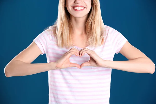 Vrouw maken van hart met haar handen op kleur achtergrond, close-up — Stockfoto