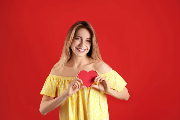 Ritratto di donna con cuore di carta su sfondo a colori — Foto Stock