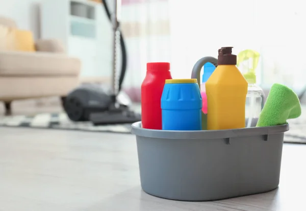 Umywalka z różnymi detergentami na podłodze w pomieszczeniu, miejsce na tekst. Usługi sprzątania — Zdjęcie stockowe