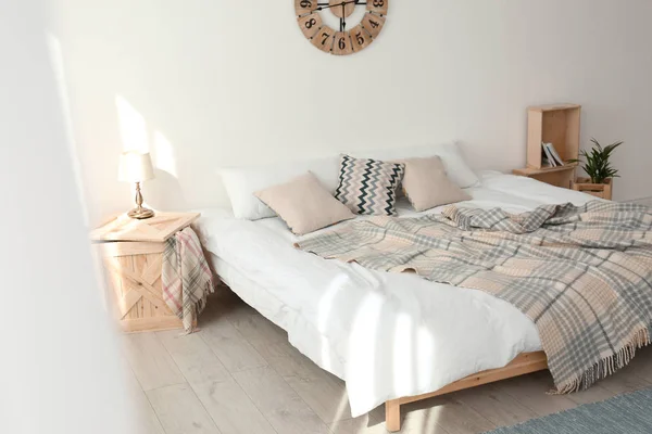 Bed with pillows and plaid in modern room interior — Stock Photo, Image