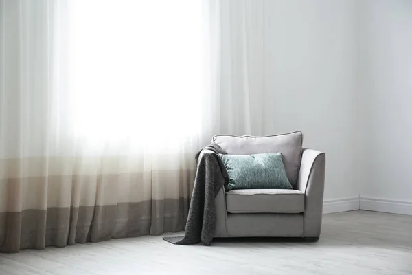 Poltrona aconchegante com travesseiros e xadrez perto da janela no quarto. Design de interiores — Fotografia de Stock