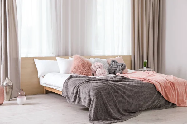 Cómoda cama con almohadas y cuadros en el interior de la habitación moderna — Foto de Stock