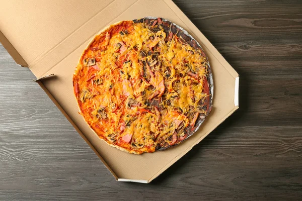 Box with black and white pizza on wooden table, top view