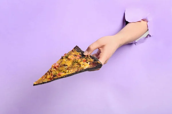 Mulher segurando fatia de pizza preta através de buraco em papel colorido, close-up — Fotografia de Stock